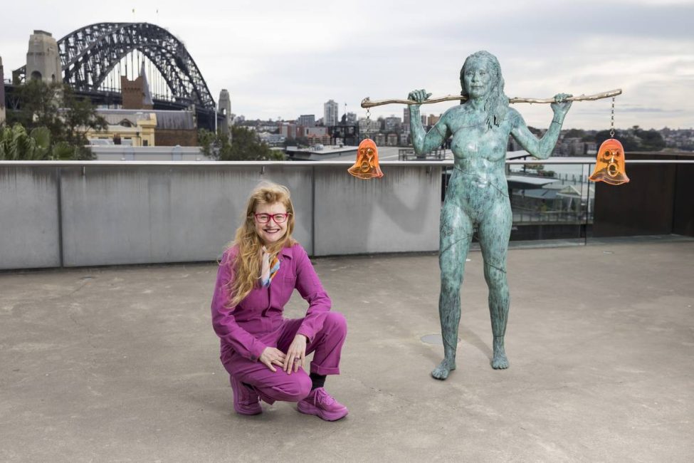 001_Nell_Holding_Both_2026_MCA.width-1200.jpegquality-70 Nell crouching by her Scultpure Installaion 'Holding Both' on the Loti Smorgon Terrace at the Museum of Contemporary Art in Sydney. In the background is the Sydney Harbour Bridge.